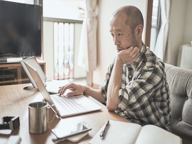 employee sitting a home workspace and working on laptop.