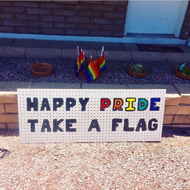sign in front of home that reads "Happy Pride Take a Flag"