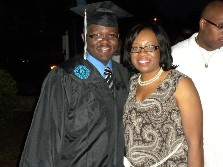 Chad in graduation cap and gown standing with mom