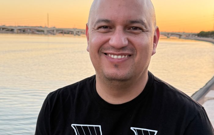 Gustavo posing outside near water during sunset.