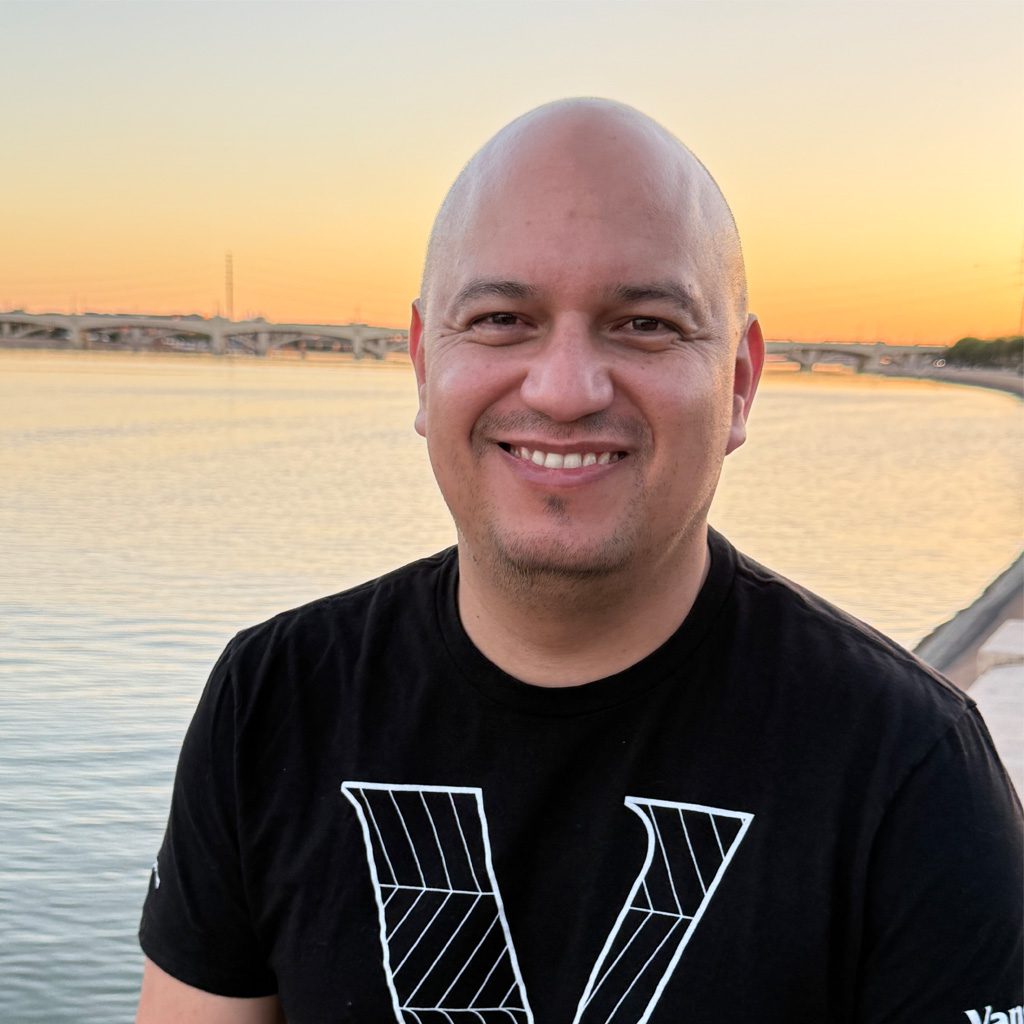 Gustavo posing outside near water during sunset.